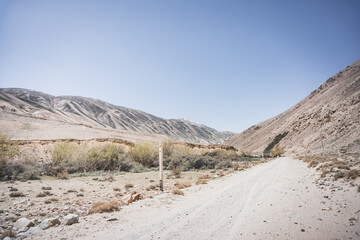 Dusty road of the Pamir Highway winds and twists in the valley of the Tien Shan Mountains in Tajikistan in the Pamirs, landscape for the background