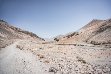 Dusty road of the Pamir Highway winds and twists in the valley of the Tien Shan Mountains in Tajikistan in the Pamirs, landscape for the background