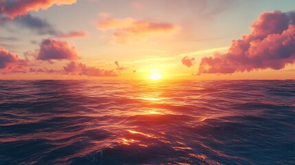 Obraz premium A stunning sunset over the ocean, with the sun setting behind fluffy pink clouds, casting a golden glow on the water.