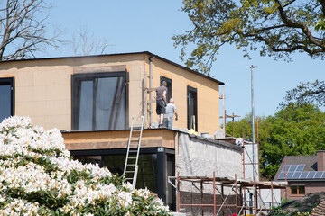 the bricklayer makes the facade of the house from gray bricks with cement and plaster at the construction site. High quality photo