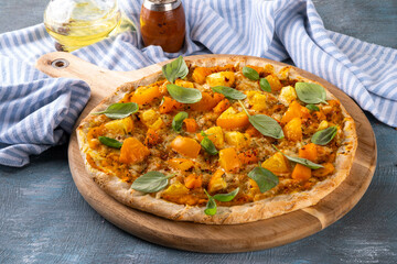 Homemade vegetarian vegetable pizza margarita with pumpkin sauce, pumpkin squash chunks and yellow tomatoes, autumn comfort warm food, copy space