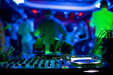 DJ turntable in the electrifying and colorful atmosphere of the club, close-up details