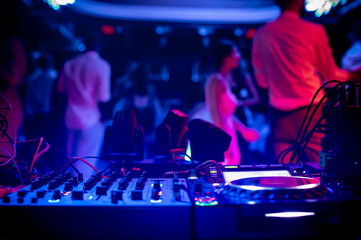 Fototapeta premium DJ turntable in the electrifying and colorful atmosphere of the club, close-up details