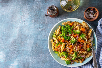Pumpkin and broccoli vegan warm pasta salad, fall season salad, autumn comfort cozy food concept 