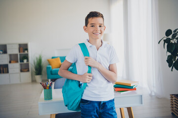 Photo of cute schoolboy carry backpack wear t-shirt modern interior apartment indoors