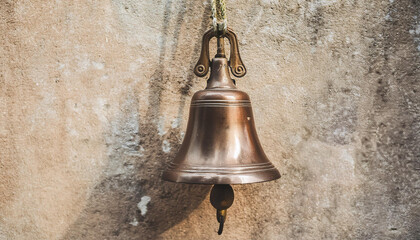 Obraz premium Vintage metal bell hanging on cement wall.