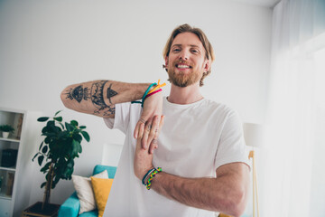 Photo of nice young man stretching wrists arms wear stylish pajama modern light cozy interior flat...