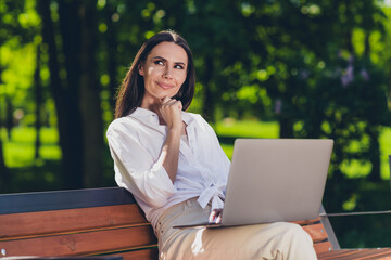 Photo of attractive young cheerful girl sit bench work netbook minded wear white garment having fun...