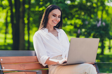 Photo of young cheerful woman sit bench work netbook wear white outfit walk park sunny summer weather outside