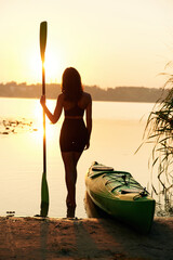 Calm and tranquil sunset time. Young woman is with the sup board on the lake