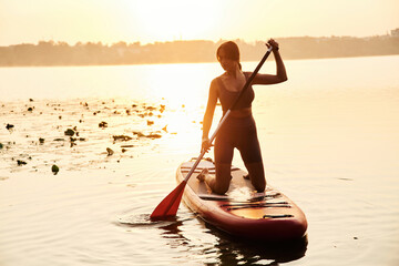 One person against sunlight. Young woman is with the sup board on the lake