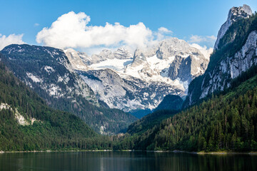 beautiful lake in the alps on a sunny day while hiking in the forest in the mountains. Snow-capped alpine mountains.