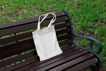 White tote cotton bag on wooden bench in the park mockup. Canvas isolated shopper, eco friendly concept. Zero waste, reusable, healthy lifestyle. Place for text, logo, design