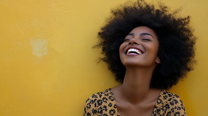 A woman with an afro hairstyle is laughing heartily against a yellow wall, capturing a moment of pure joy and happiness that radiates positivity and vibrancy.