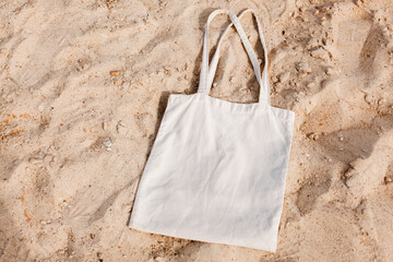 White cotton or mesh bag on beach sand background. Zero waste, no plastic, eco friendly shopping,...