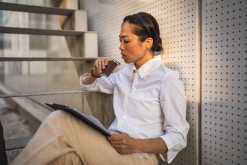 mature japanese woman sit outdoor hold flask and drink alcohol