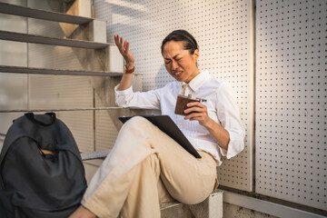 mature japanese woman sit outdoor hold flask and have migraine