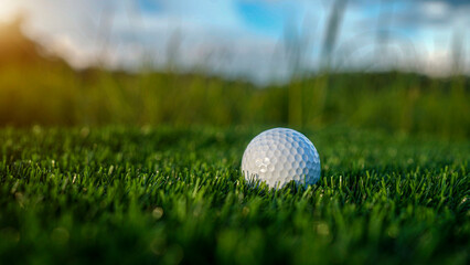 Golf ball is on a green lawn in a beautiful golf course with morning sunshine.