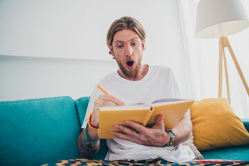 Photo of attractive young male sit couch write notebook dressed sleepwear cozy day light home...