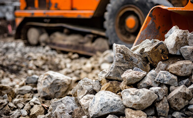 Naklejka premium A pile of rocks and stones with a construction vehicle in the background at a worksite.