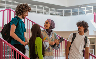 Fototapeta premium A group of happy diverse college students hanging out they are talking with each other while walking in the university hallway.