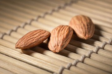 Several almonds on a wooden background with soft lighting, selective focus.