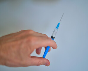 a fragment of a human hand holds a syringe