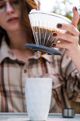 Making filter coffee. Go. Hot drink in nature. Coffee in the car. Autumn forest. Car trip. Autumn. Coffee devices. Pour water. Pour coffee. Earth. Vertical photo