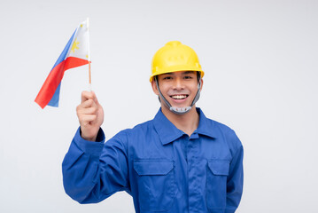 A Filipino seaman or construction worker in blue coveralls and a yellow hard hat proudly holds the...