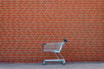 An empty shopping cart stands against the wall of a supermarket