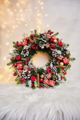 classic Christmas wreath in red with cinnamon and pinecones on a white background with lights © Vieille Prune