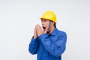 A worker in a yellow hard hat yawns, showing signs of exhaustion and tiredness on the job. Ideal for representing work fatigue, sleep deprivation, and workplace challenges.