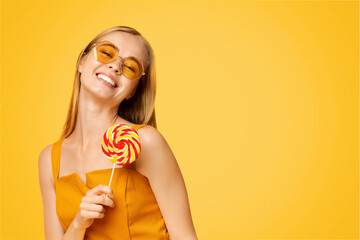 Sweet Summer. Carefree Teen Girl Holding Big Bright Lollipop And Smiling At Camera, Posing Over Yellow Background, Closeup Portrait