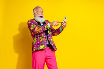 Photo of attractive retired man excited click hold gadget dressed stylish colorful fancy clothes isolated on yellow color background