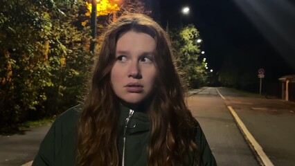 young woman walking alone on dark street at night and afraid. concept danger, turns back