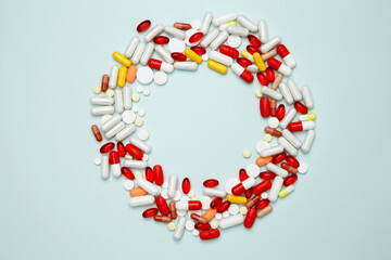 Various colorful pills and capsules scattered on a light blue background. Concept of medicine, healthcare, and pharmaceutical industry