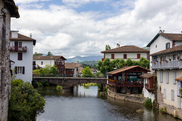 Obraz premium Village de Saint Jean Pied de port avec des bâtiments typiques, un pont et une rivière, cité médiévale