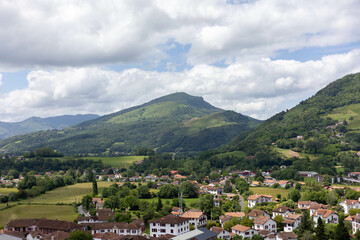 Paysage du Pays basque Français avec un ciel nuageux, une montagne et un petit village entouré de...