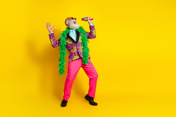 Full size photo of overjoyed elderly man sing mic empty space wear vibrant outfit isolated on yellow color background