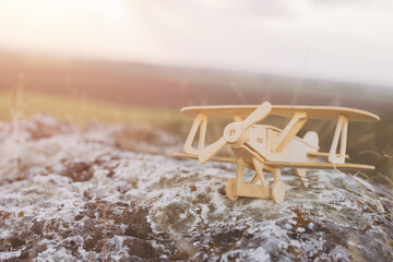 Wooden Model Airplane on Rocky Surface at Sunset with Dreamy Background