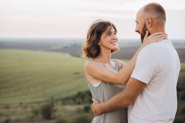Obraz premium Happy Couple Embracing Outdoors in Scenic Field at Sunset, Expressing Love and Connection
