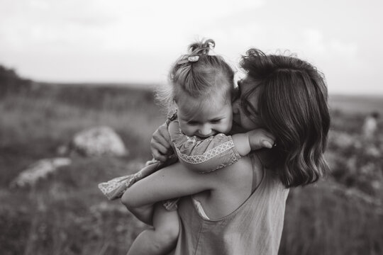 Tender Moment Between Mother and Daughter in a Serene Outdoor Setting Captured in Black and White Photography