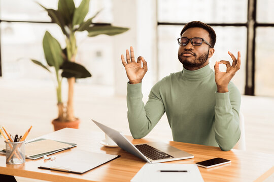 Relaxation At Work. Afro businessman meditating at work, dealing with stress and anxiety. Free space