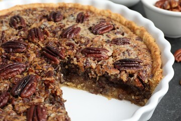 Delicious pecan pie in baking dish on table, closeup
