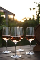 Tasty wine in glasses on wooden table outdoors