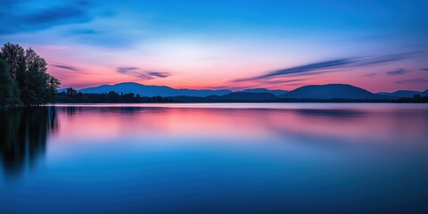 A stunning purple twilight reflects over a calm lake, with soft hues of pink and blue in the sky, and distant hills framing the serene water.