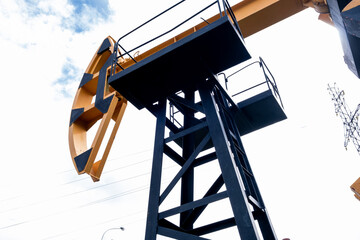 Oil rig pump rocking chair against. Crude oil production from the ground. Petroleum production, natural gas. The concept of oil production and the cost of a barrel of oil