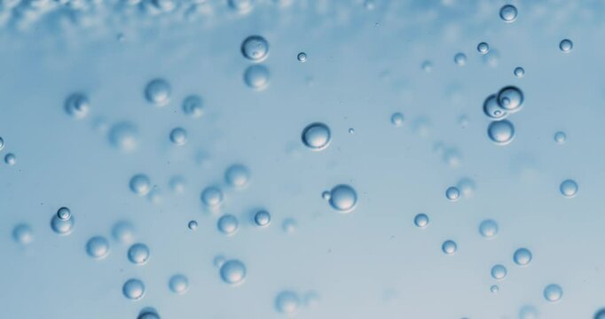 Many water bubbles in blue water close up, abstract water wave with bubbles in slow motion.
