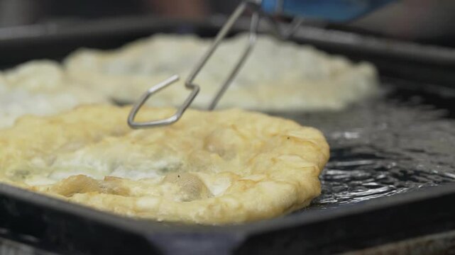 Fried flatbread (L&aacute;ngos in Hungarian language) frying in oil.
