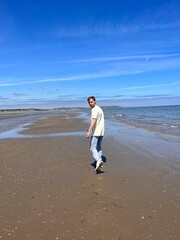 Handsome blond man walking on the beach, back view